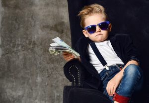 Cool kid sitting in a chair with sunglasses and a handful of cash.