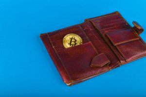 Leather wallet and gold coin with a bitcoin symbol.