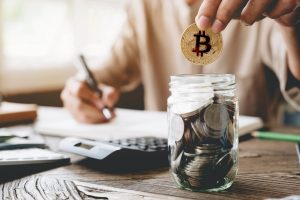 Businessman putting bitcoin into piggy bank and using calculator