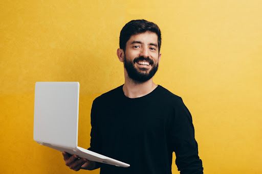 smiling man holding a laptop