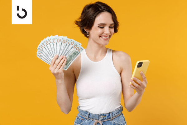 woman holding cash and phone
